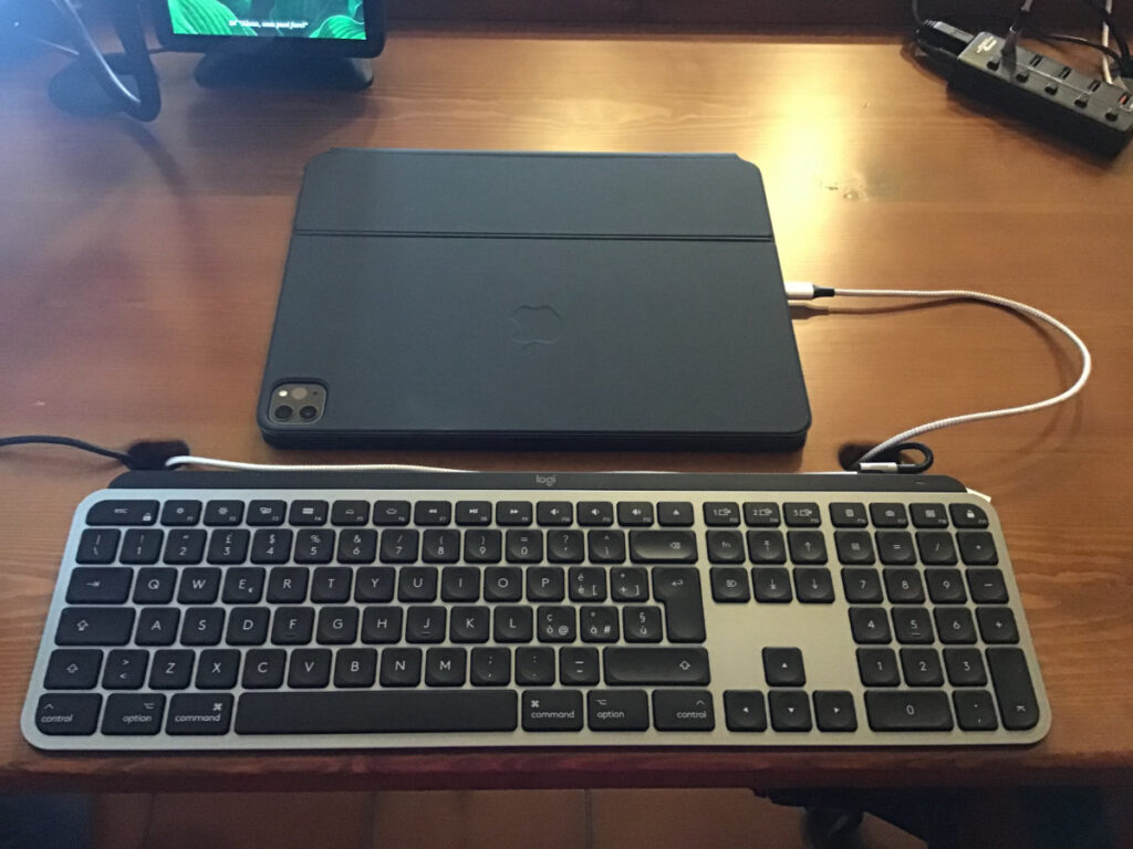Disabili DOC – L'immagine mostra l'iPad Pro 12,9" 2020 inserito nella Magic Keyboard chiusa, all'iPad è collegato un cavo magnetico per la ricarica